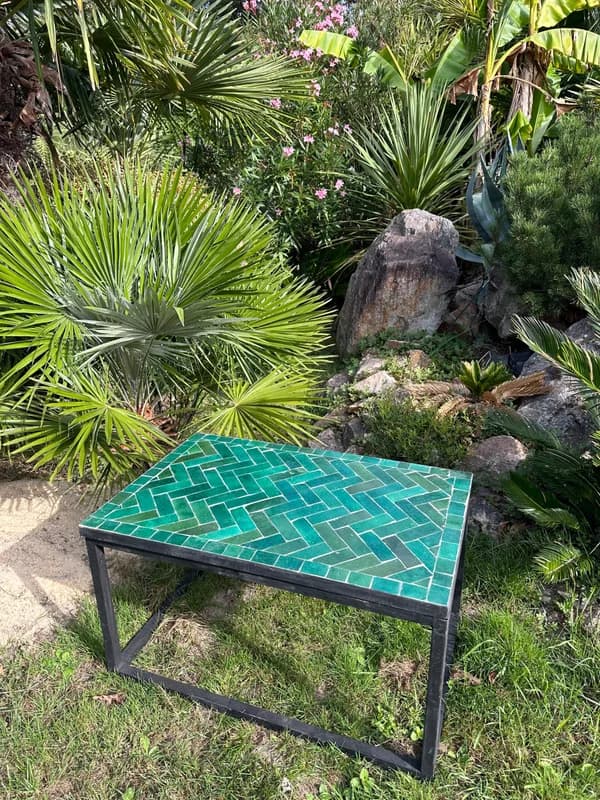 Turquoise Zellige table among lush garden plants, viewed at an angle