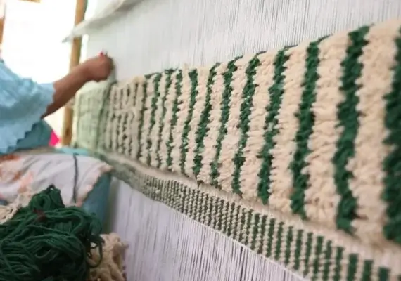 Marokkanische Kunsthandwerkerin knüpft einen authentischen Berber Teppich – Benihaus Qualität.